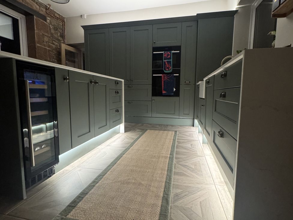 A kitchen with cabinets and a wine cooler at Yew Tree Cottage in Mealsgate near Ireby