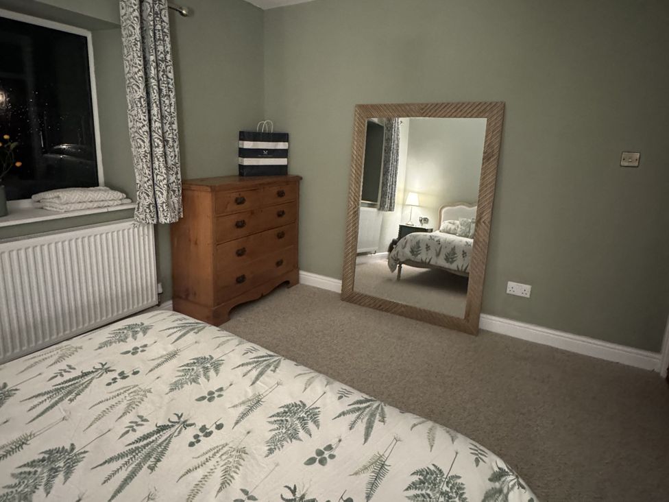 A bedroom with a bed and dresser at Yew Tree Cottage in Mealsgate near Ireby