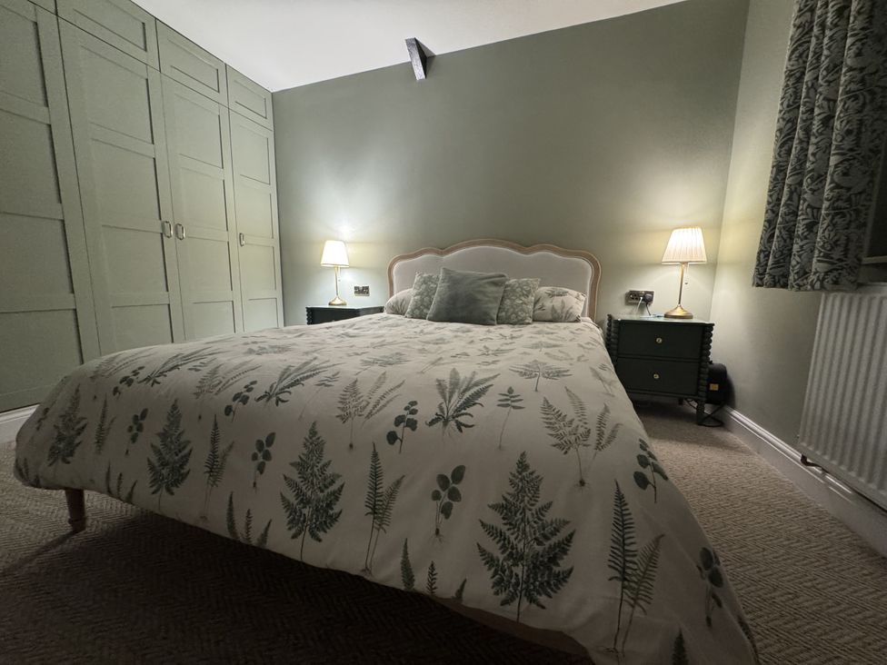 A bedroom with a bed and wardrobe at Yew Tree Cottage Mealsgate near Ireby