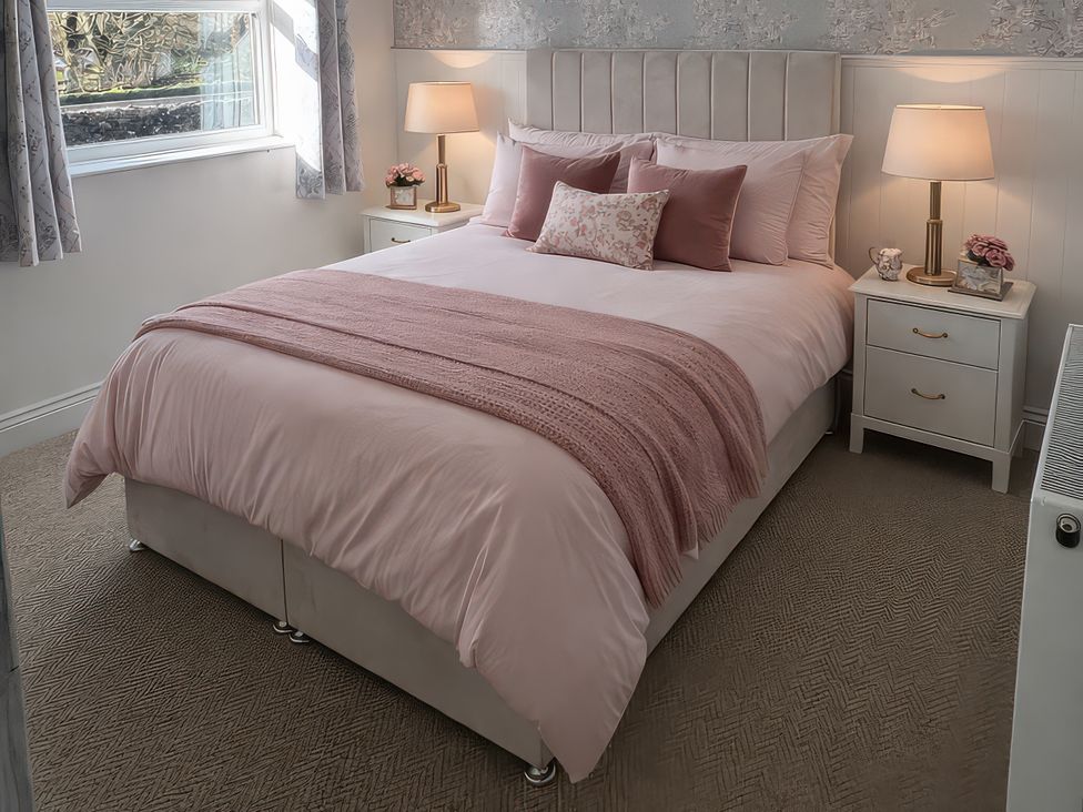 A bedroom with a bed and bedside tables at Yew Tree Cottage Mealsgate near Ireby