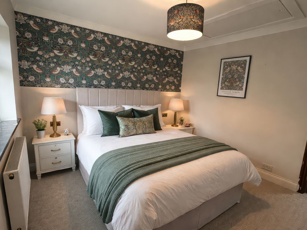 A bedroom with a bed and bedside tables at Yew Tree Cottage Mealsgate near Ireby