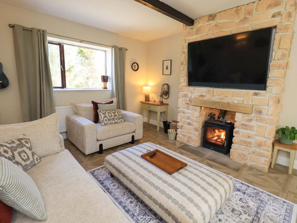 A living room with a fireplace and a television at Yew Tree Cottage Mealsgate near Ireby