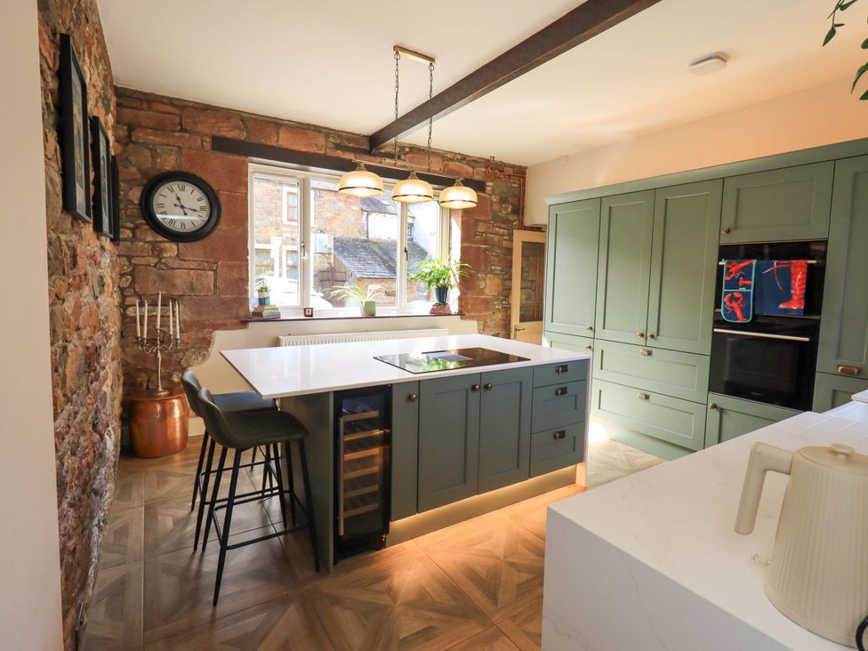 A kitchen with an island and cabinets at Yew Tree Cottage Mealsgate near Ireby