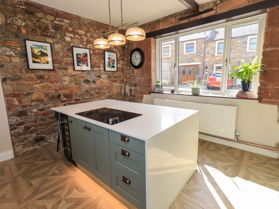 A kitchen with a stone wall and island at Yew Tree Cottage Mealsgate near Ireby