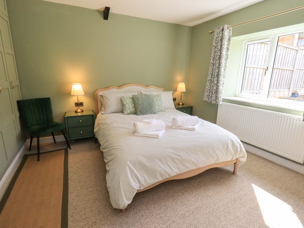 A bedroom with a bed and a chair at Yew Tree Cottage Mealsgate near Ireby