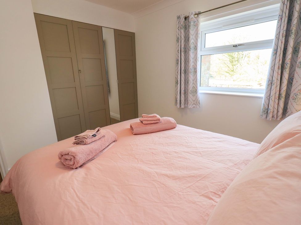 A bedroom with a bed and towels at Yew Tree Cottage Mealsgate near Ireby
