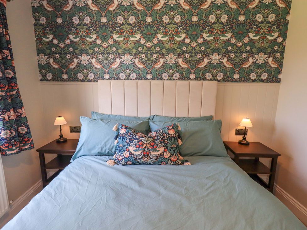 A bedroom with a bed and bedside tables at Yew Tree Cottage Mealsgate near Ireby