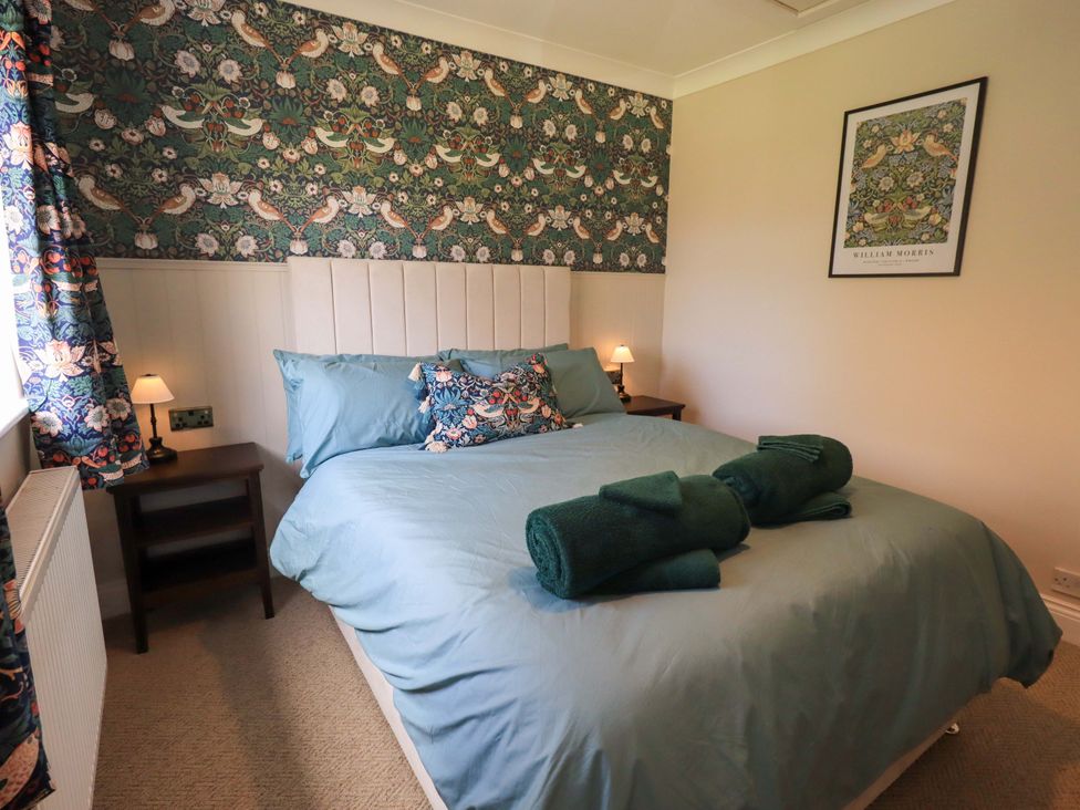 A bedroom with a bed and nightstand at Yew Tree Cottage Mealsgate near Ireby