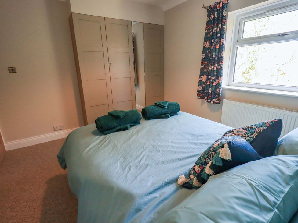 A bedroom with a bed and wardrobe at Yew Tree Cottage Mealsgate near Ireby