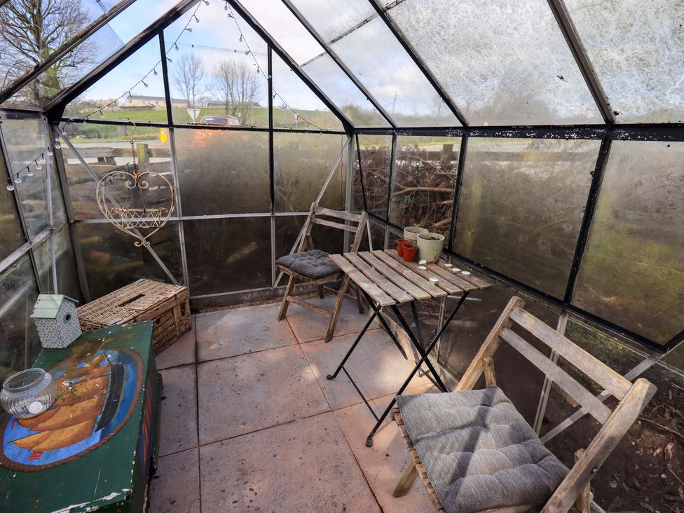 A greenhouse with chairs and a table at Yew Tree Cottage, Mealsgate near Ireby