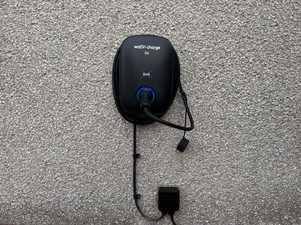 An electric vehicle charger mounted on a wall at Yew Tree Cottage in Mealsgate near Ireby