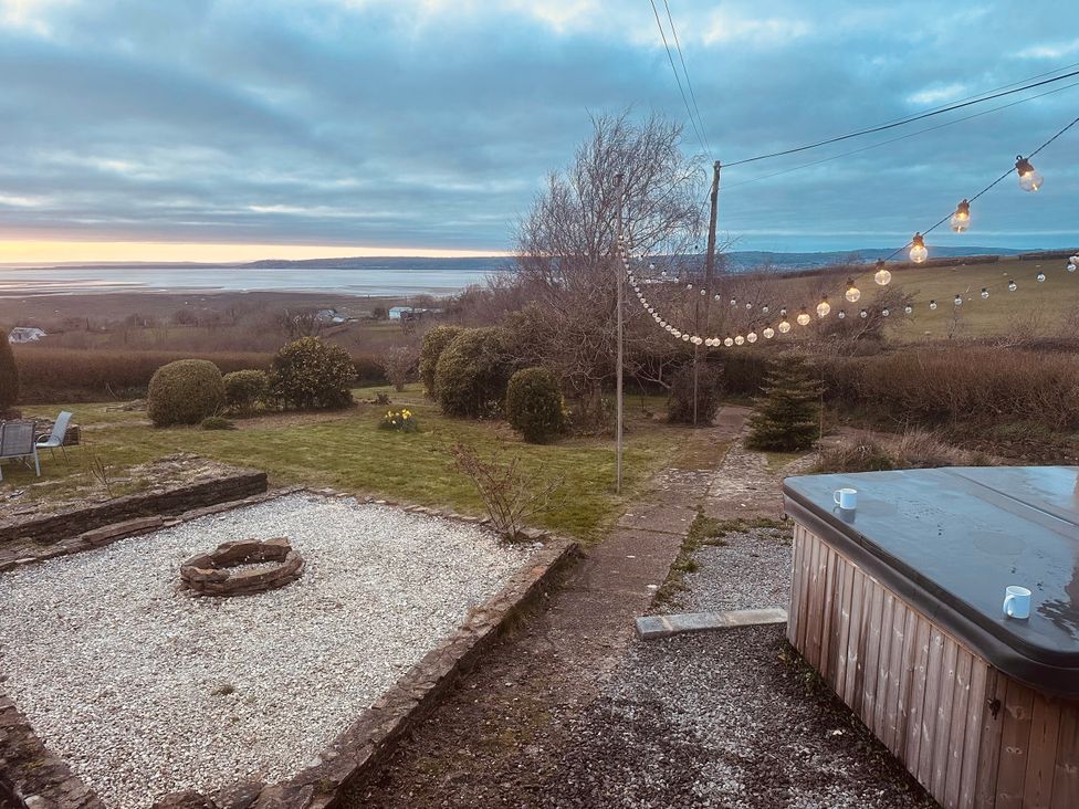 A garden with a fire pit and hot tub at Burry House in Llanmorlais