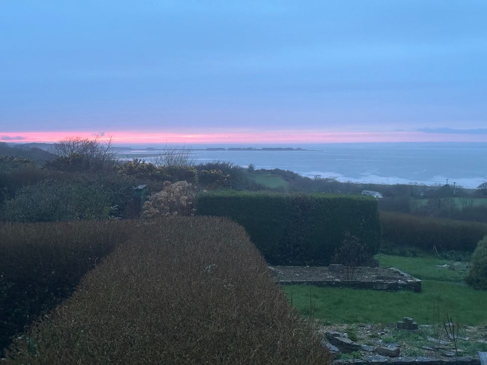 A coastal view with bushes and the ocean at Burry House Llanmorlais