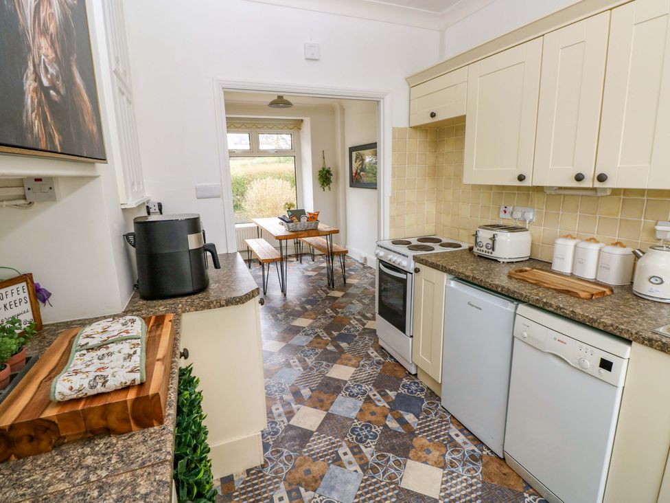 A kitchen with appliances and a dining table at Burry House Llanmorlais