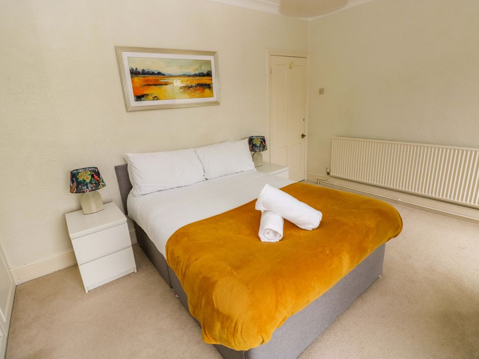 A bedroom with a bed, nightstand, and painting at Burry House Llanmorlais