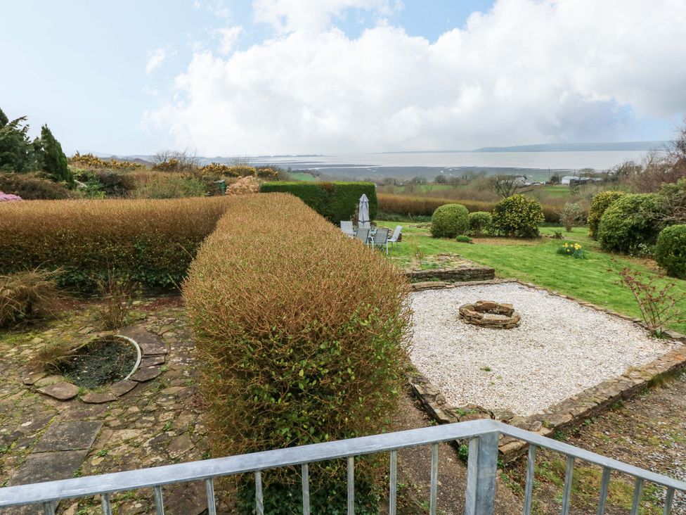 A garden with hedges and a fire pit at Burry House Llanmorlais