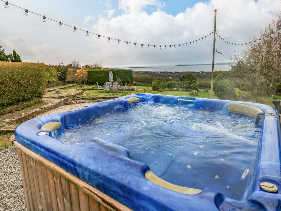 A hot tub in a garden with chairs and pathway at Burry House Llanmorlais