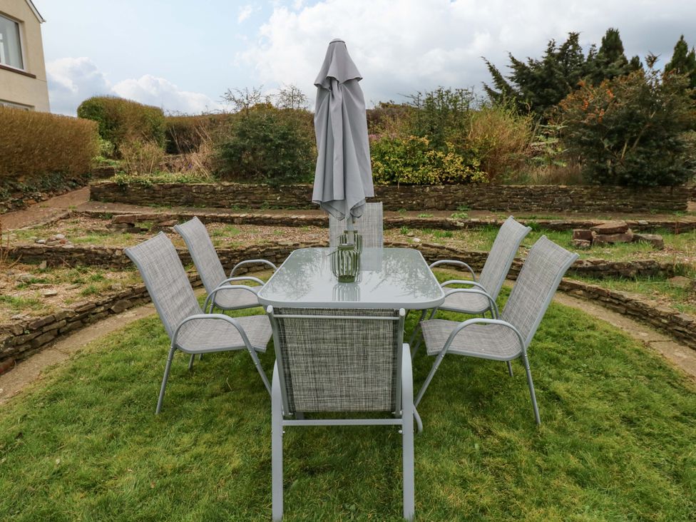 A garden with a table and chairs under an umbrella at Burry House Llanmorlais