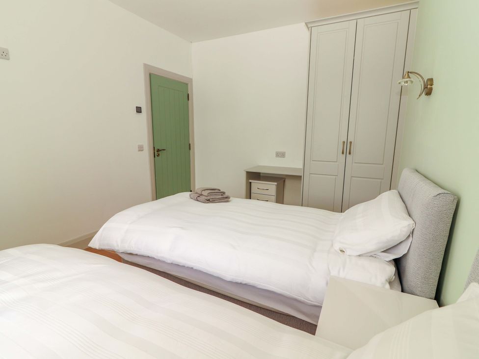 A bedroom with two beds and a wardrobe at Teach Ti in Miltown Malbay