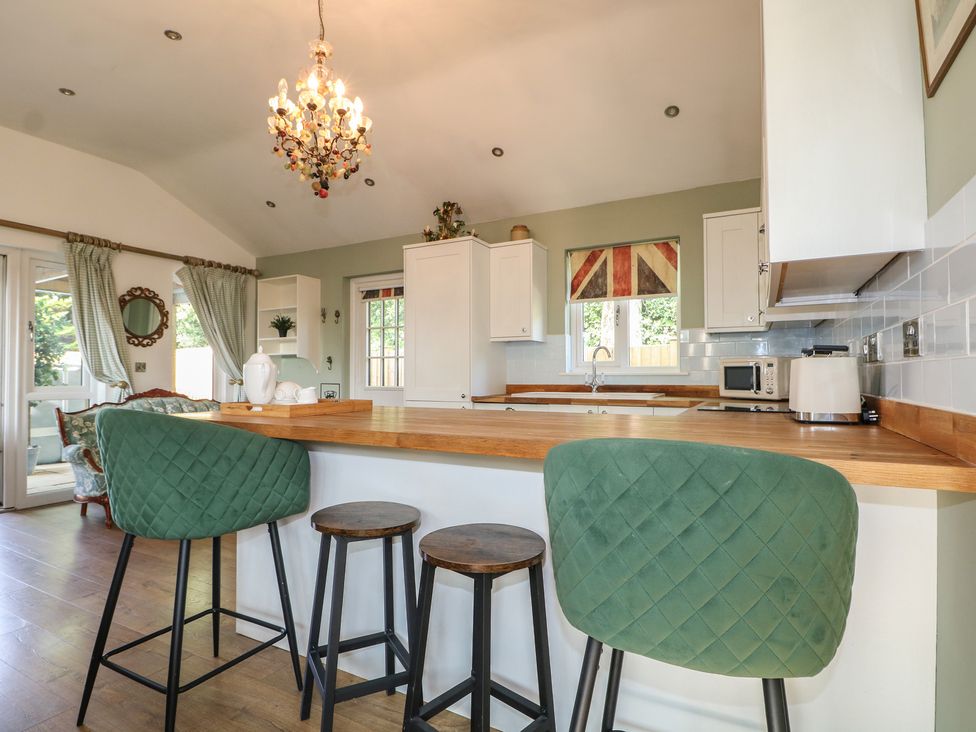 A kitchen with a chandelier and bar stools at El -Nido in Alton