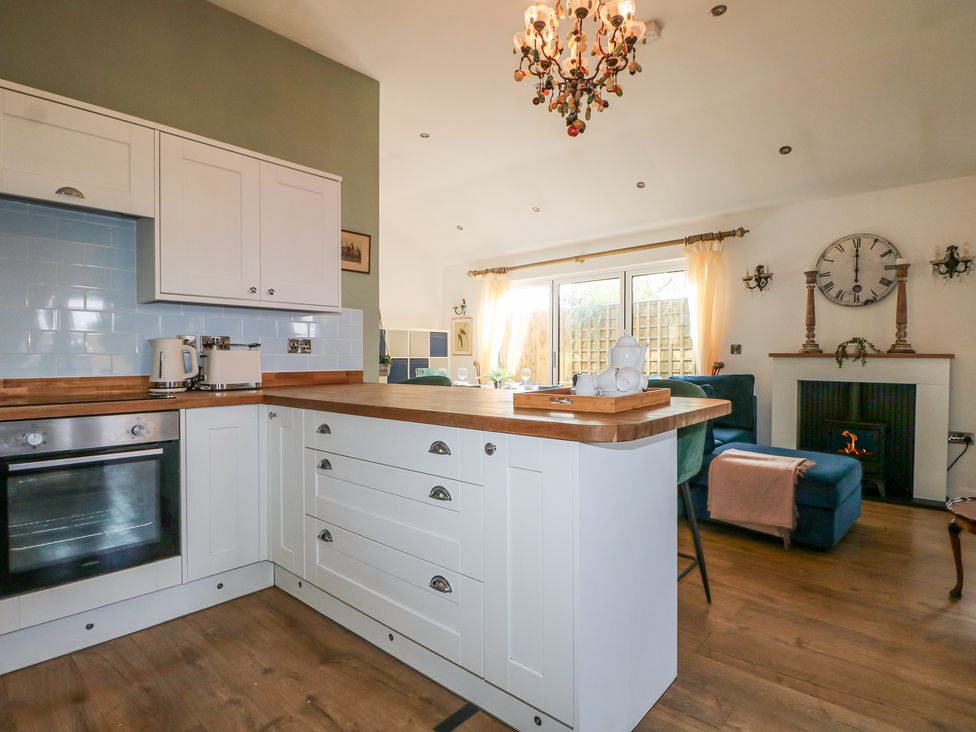 A kitchen with white cupboards and a small dining area at El -Nido in Alton