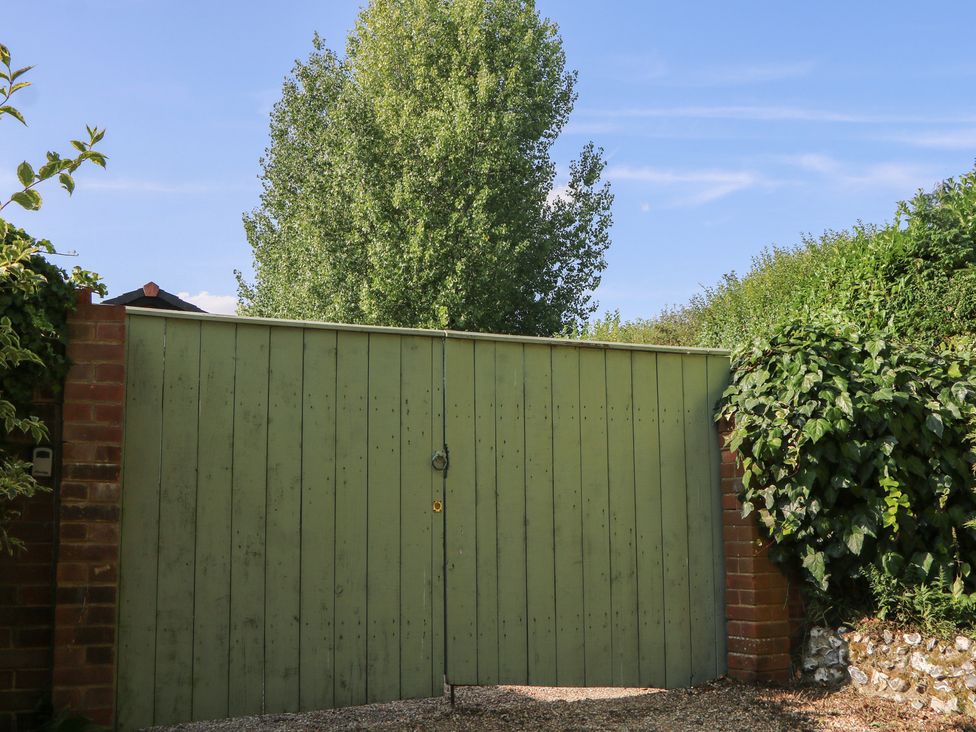 A green gate with a tree and shrubs at El-Nido in Alton