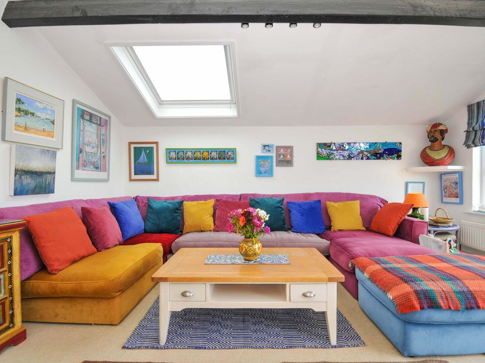 A living room with a colorful sectional sofa and a wooden coffee table at 5 Esplanade in Fowey