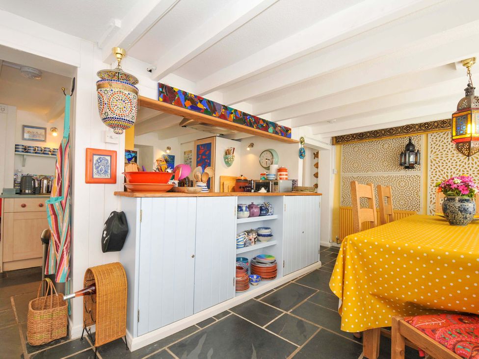 A kitchen and dining area with a yellow polka dot tablecloth on the table and wooden chairs at 5 Esplanade in Fowey