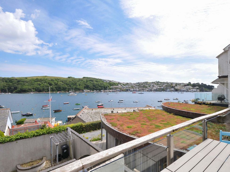 A balcony overlooking a harbor with boats and hillside houses at 5 Esplanade in Fowey