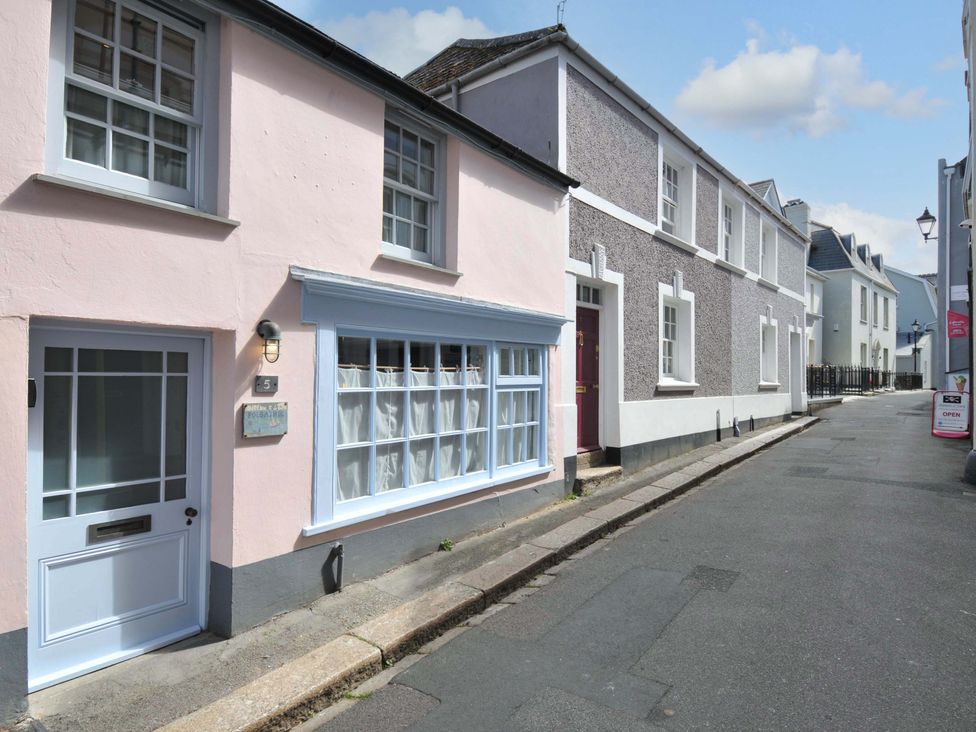 A narrow street with pastel-colored terraced houses and a pale pink house with white framed windows at 5 Esplanade in Fowey