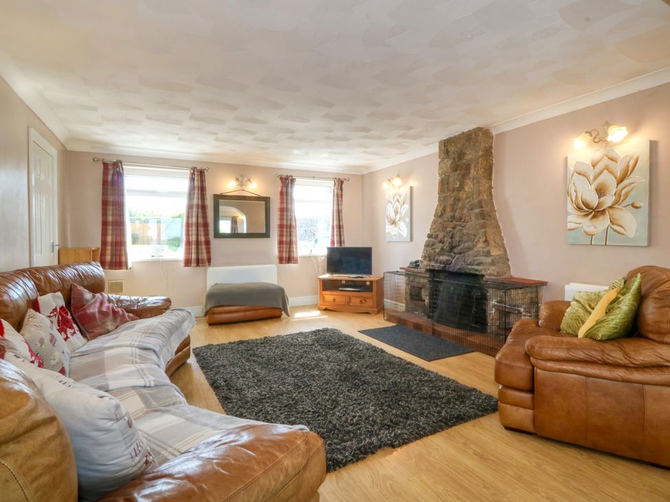 A living room with a fireplace and seating at Llain Delyn in Capel Mawr near Malltraeth
