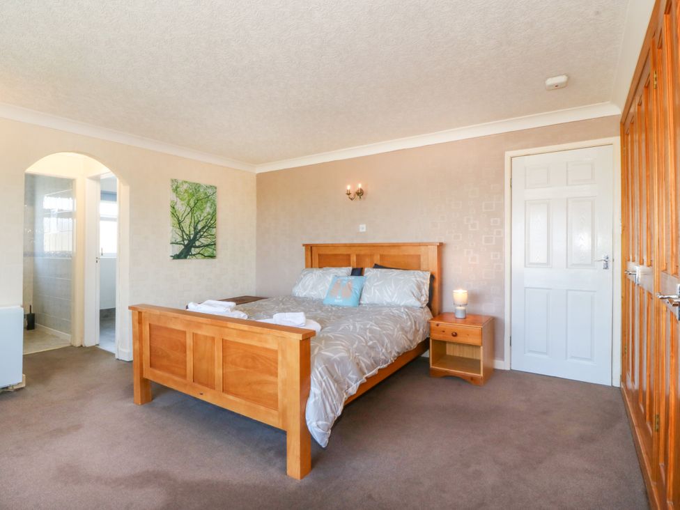 A bedroom with a bed and wooden furniture at Llain Delyn Capel Mawr near Malltraeth