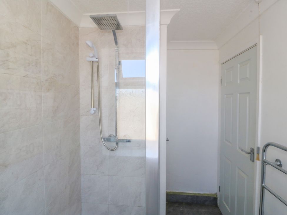 A bathroom with a shower and a door at Llain Delyn Capel Mawr near Malltraeth