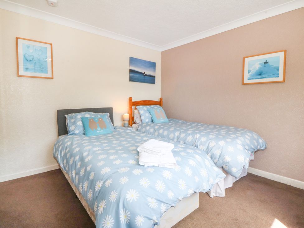 A bedroom with two single beds and wall art at Llain Delyn in Capel Mawr near Malltraeth