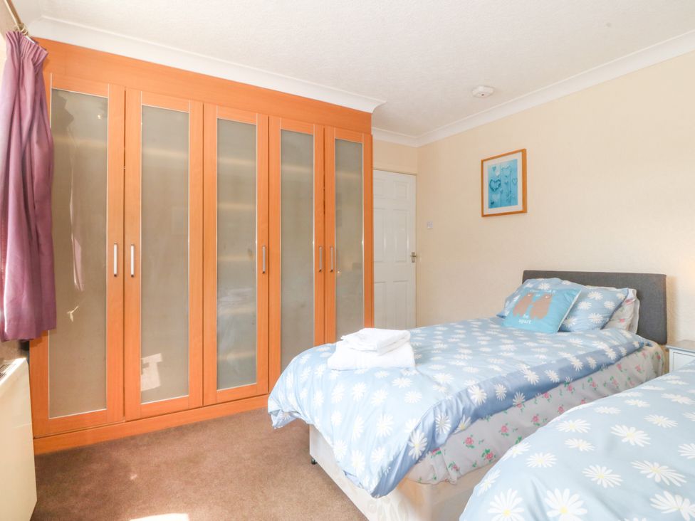 A bedroom with beds and wardrobe at Llain Delyn Capel Mawr near Malltraeth