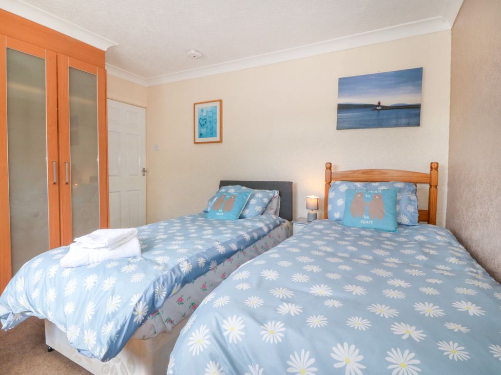 A bedroom with two single beds and a wardrobe at Llain Delyn in Capel Mawr near Malltraeth