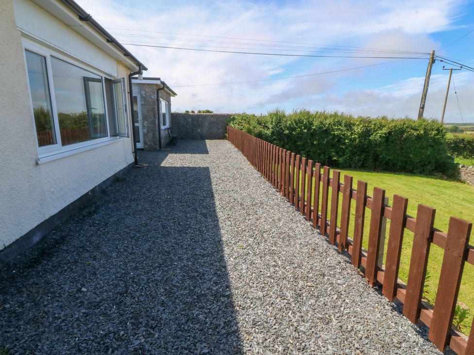 An outdoor area with gravel and a wooden fence at Llain Delyn in Capel Mawr near Malltraeth