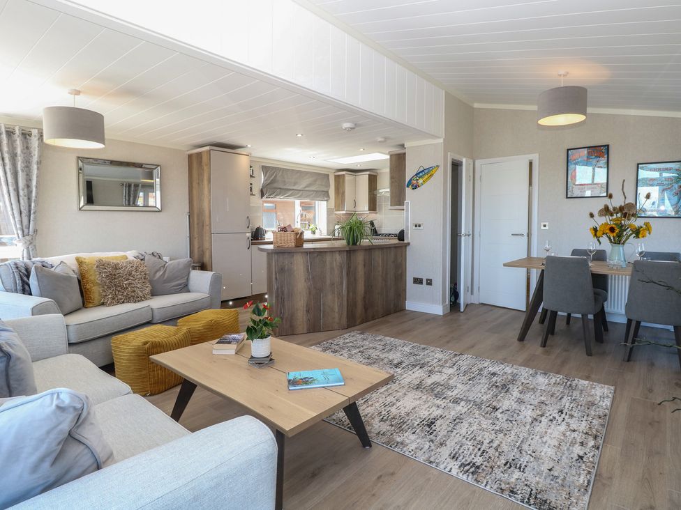A living room with a sofa, coffee table, and dining area at Life's a Beach in Bacton