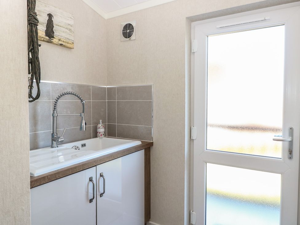 A laundry room with a sink and cabinet at Life's a Beach in Bacton