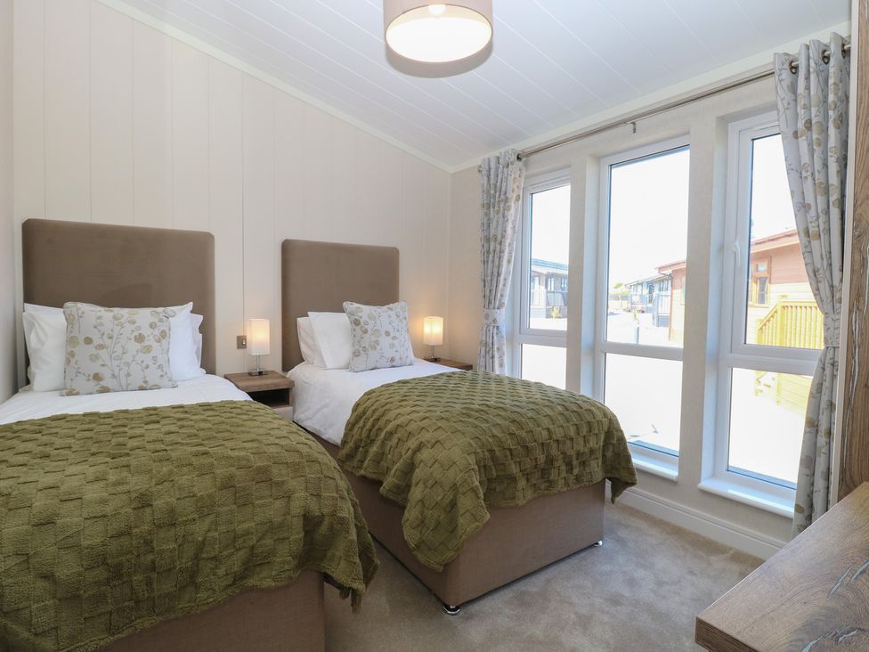 A bedroom with twin beds and windows at Life's a Beach in Bacton