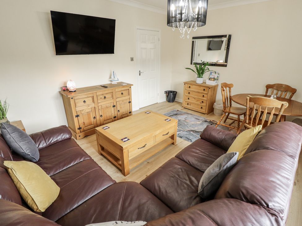 A living room with a sofa, coffee table, and television at 5 Links Court in Skegness