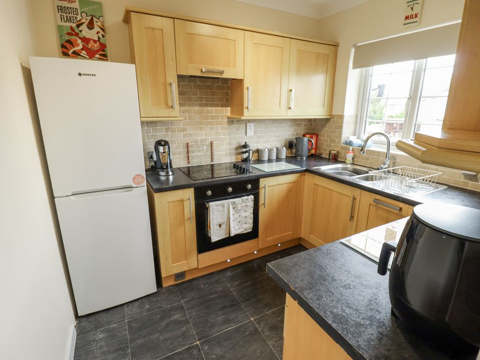 A kitchen with cabinets, stove, fridge, and sink at 5 Links Court in Skegness