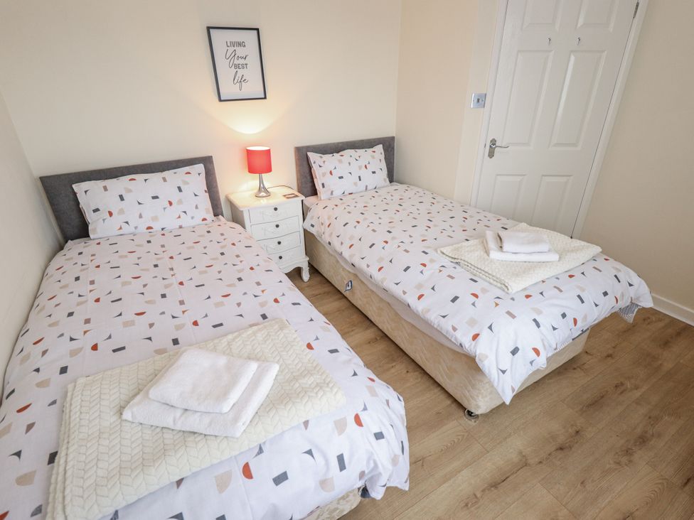 A bedroom with two beds and a nightstand at 5 Links Court in Skegness