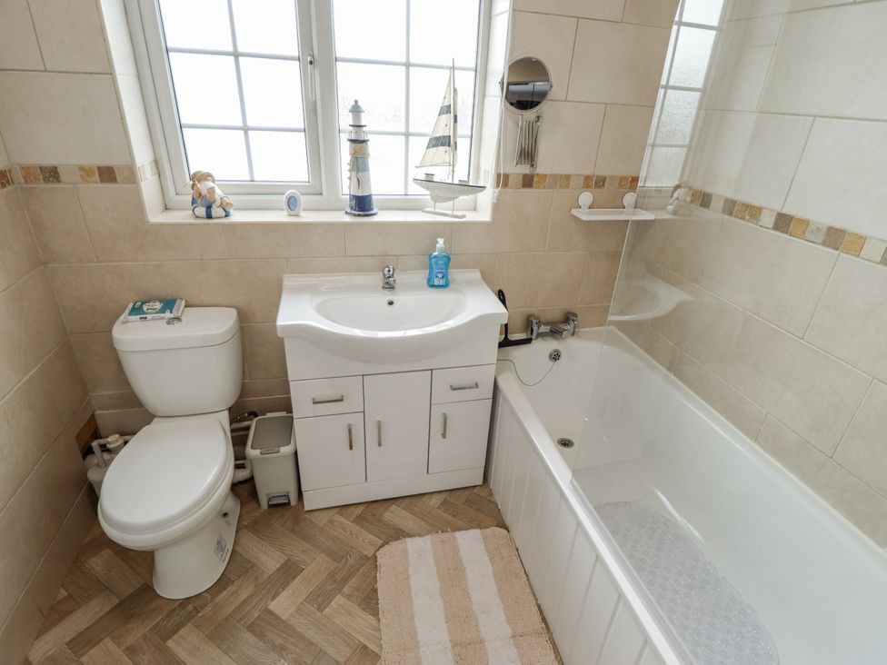A bathroom with a toilet, sink, and bathtub at 5 Links Court in Skegness