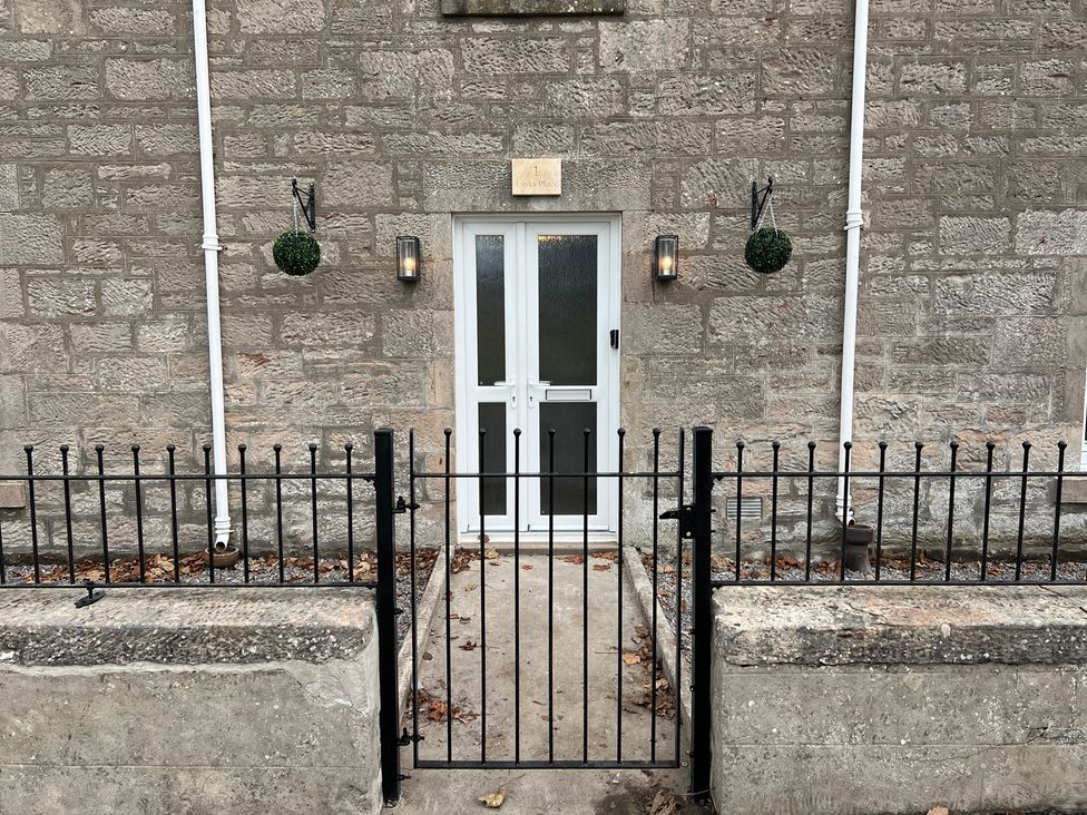 An outdoor entrance with a front door and metal gate at 1 Links Place Nairn
