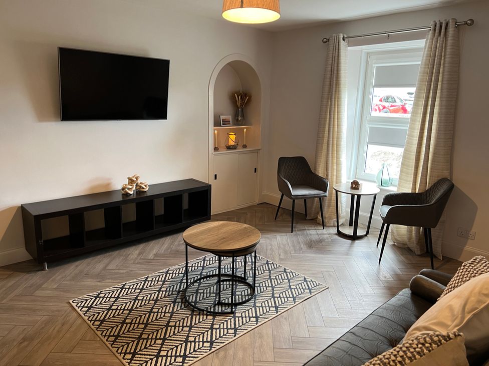A living room with a television and coffee table at 1 Links Place Nairn