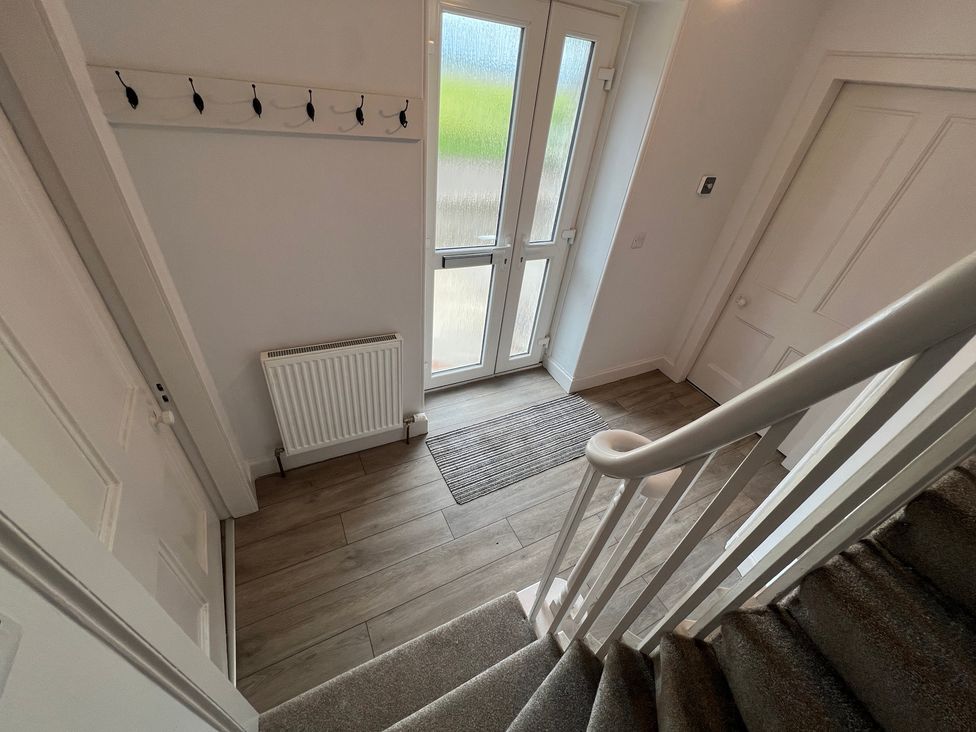 A hallway with coat hooks and a staircase at 1 Links Place Nairn