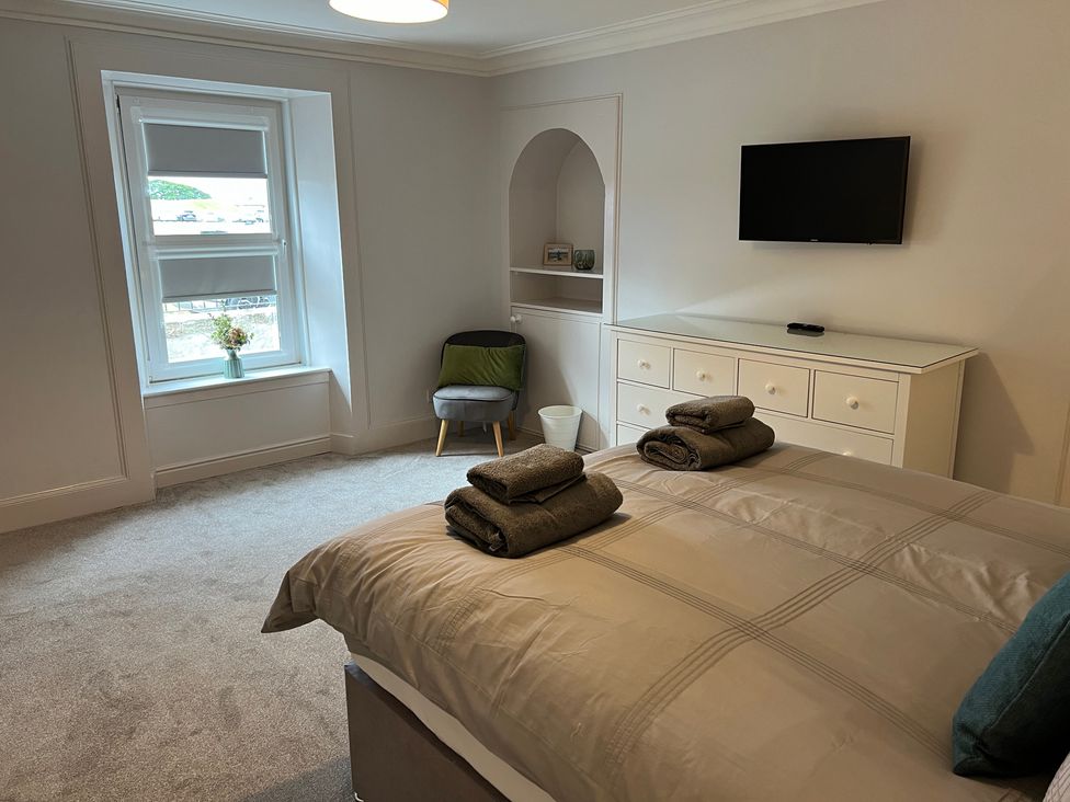 A bedroom with a bed and television at 1 Links Place in Nairn