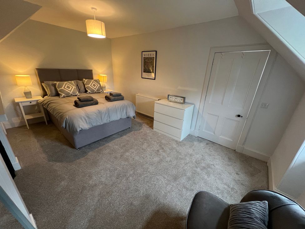 A bedroom with a bed and nightstands at 1 Links Place in Nairn