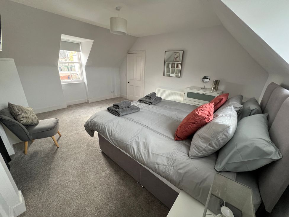 A bedroom with a bed and a chair at 1 Links Place in Nairn